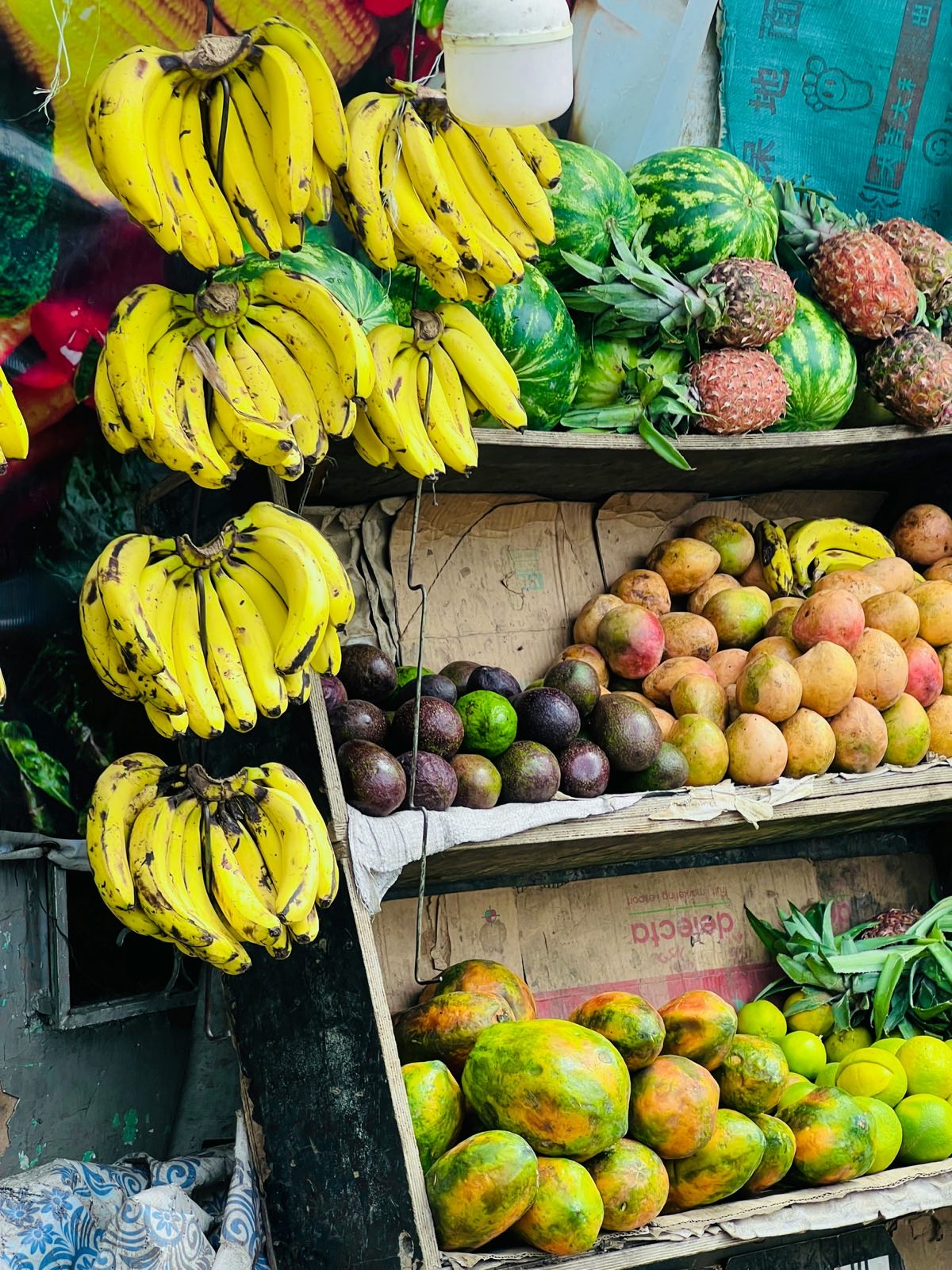 A Tanzanian fruit vendor's stall stocked with bananas, watermelons, pineapples and papayas