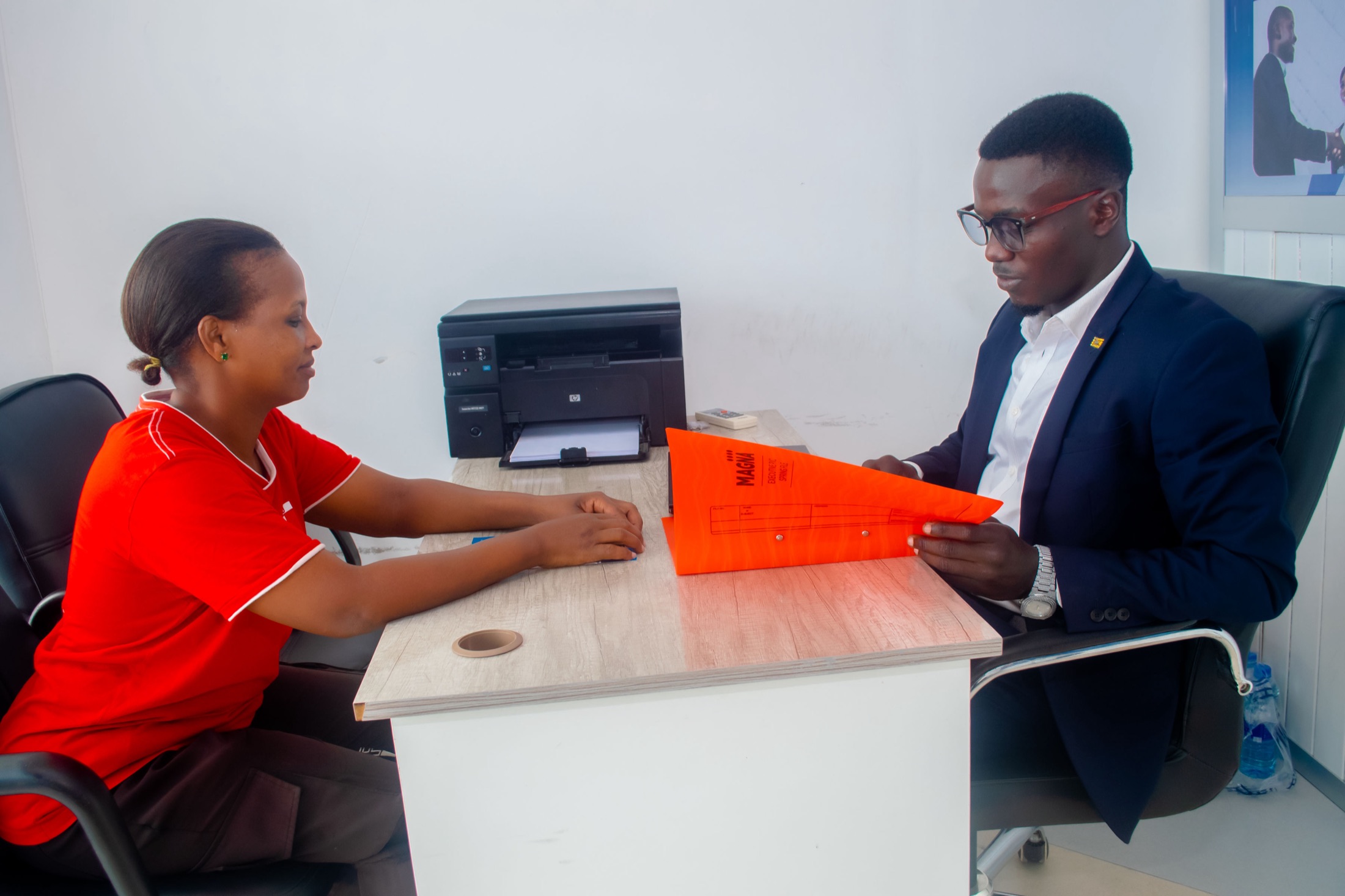 A BSI Finance loan officer reviewing a client's loan file at the Tegeta head office